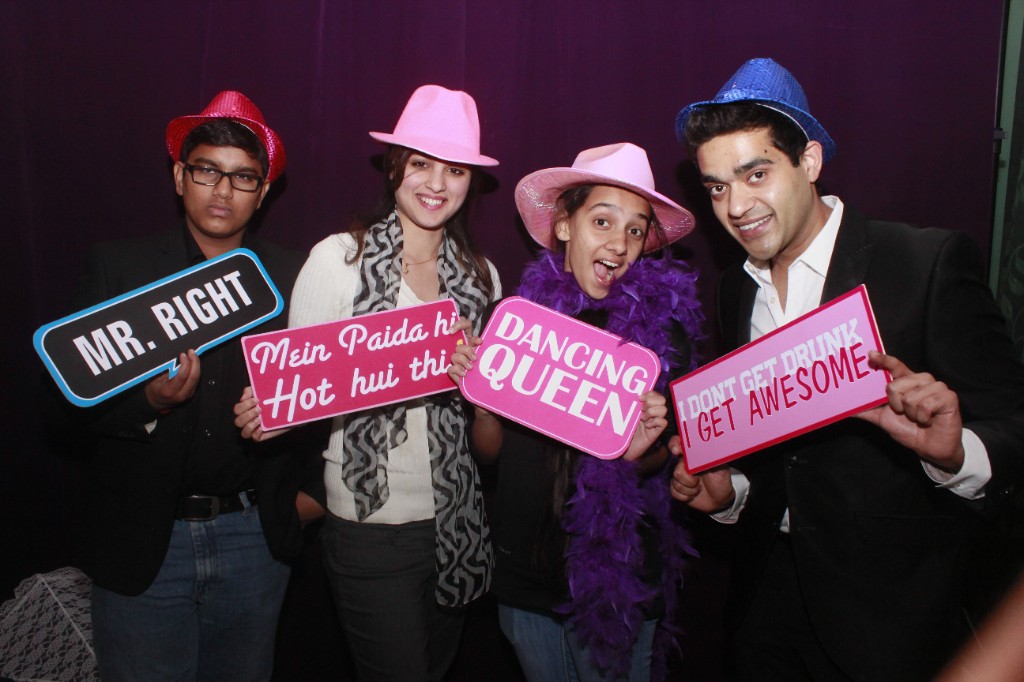 Young guests posing with festive hats and playful signs at a company celebration photo booth