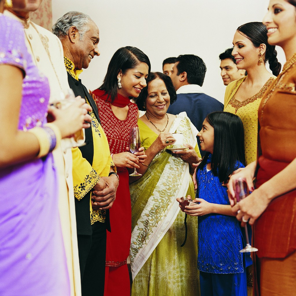 Multi-generational Indian family in festive attire talking warmly at a company social gathering