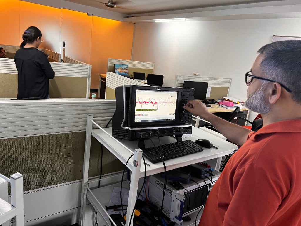Engineer adjusting a digital storage oscilloscope showing multi-channel switching waveforms