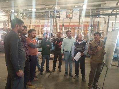 Trainer pointing at whiteboard while operators hold check sheets during plant training